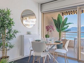 Ein Balkon mit Esstisch für zwei Personen, einem Blumentopf und Blick auf das Meer.