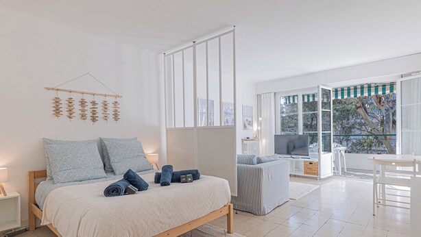 Quarto moderno com cama, televisão e varanda.