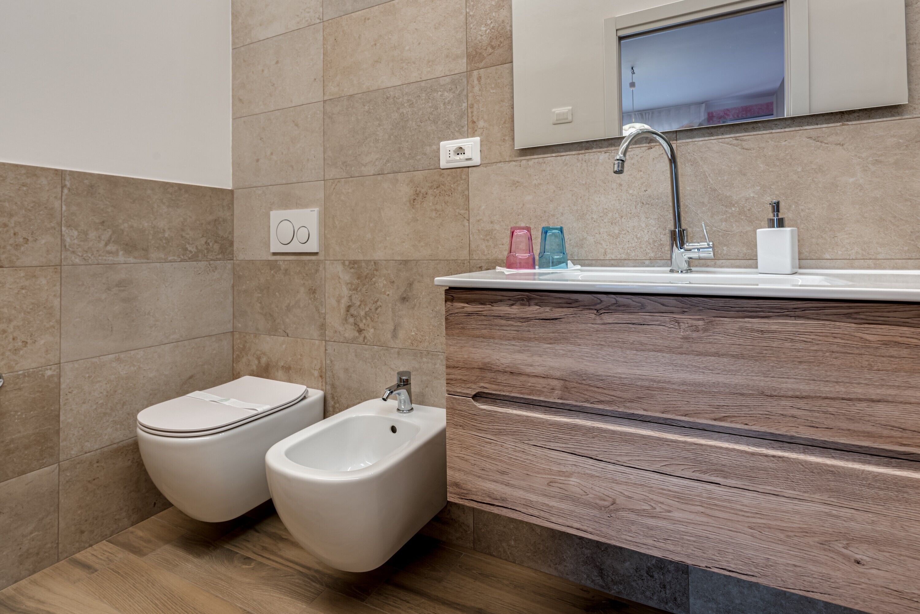 A modern bathroom with a bidet, a sink, and a mirror above it.