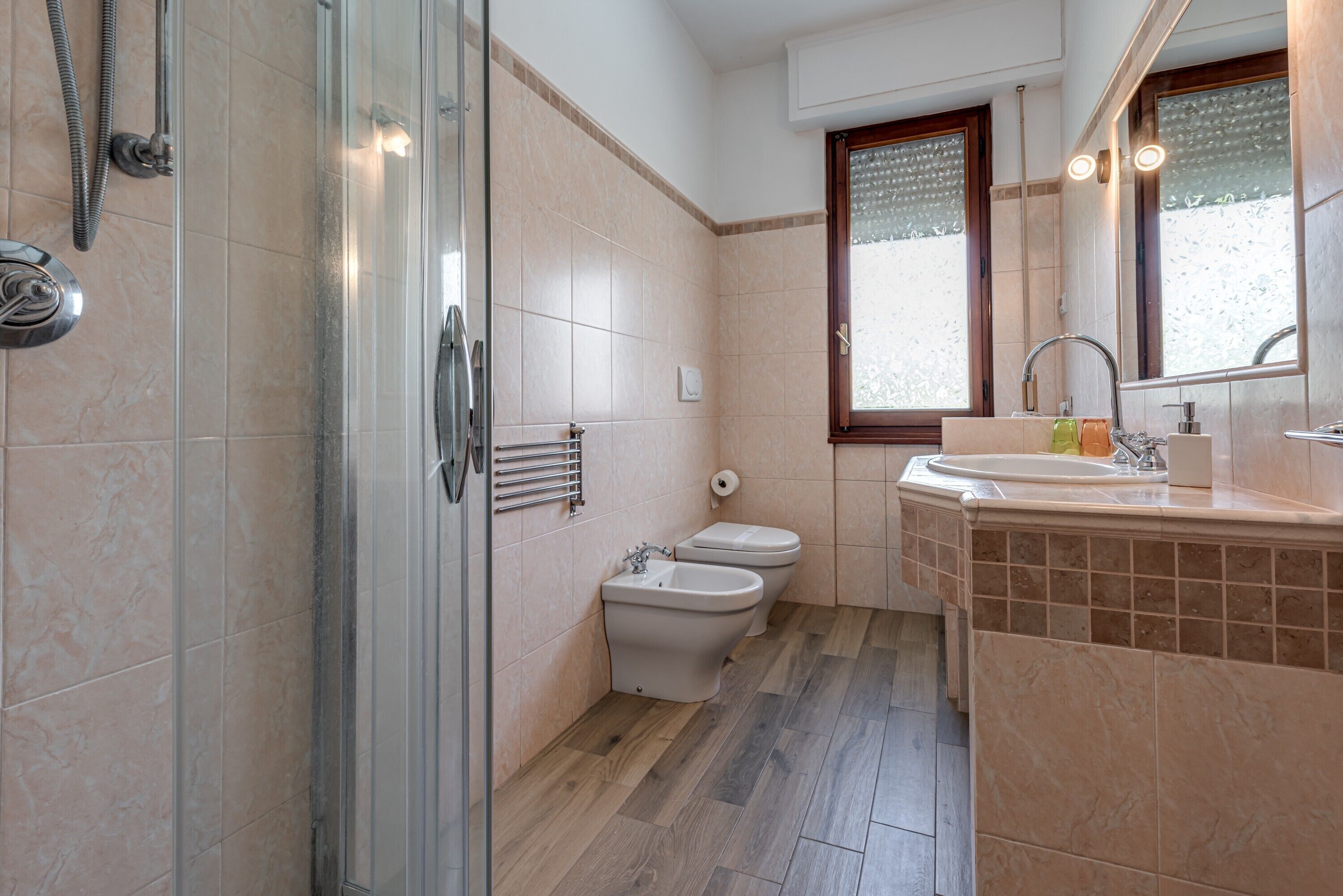 Une salle de bain avec une douche à parois de verre, un bidet, des toilettes et un lavabo avec un miroir au-dessus.