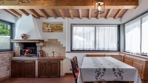 A rustic kitchen with wooden beams, a fireplace, and a dining area with a table.