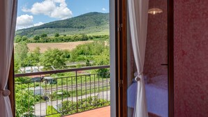 A balcony with a view of a green landscape and a railway track.