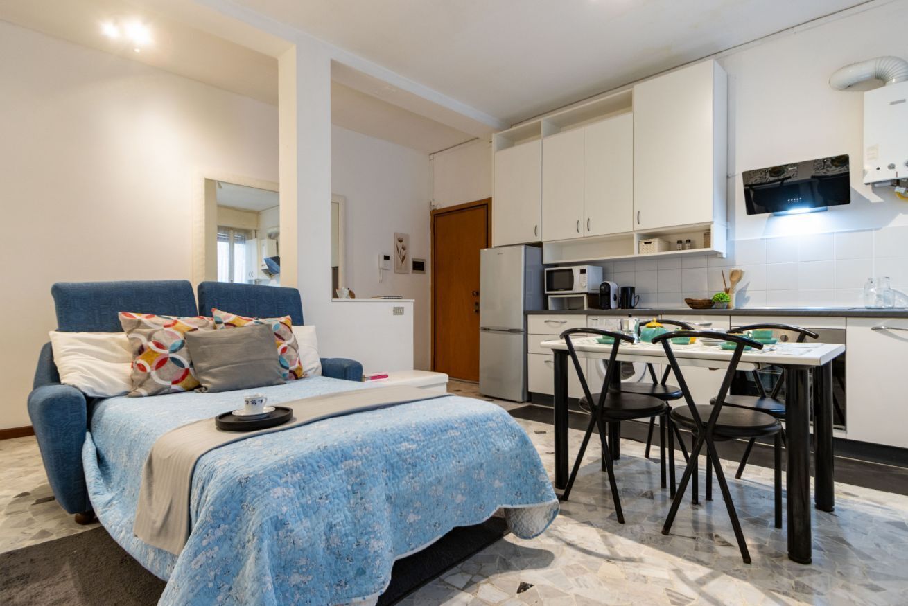 Ein kleines Zimmer mit einem Bett, einem kleinen Esstisch und einer Küchenzeile.