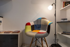 Ein Sessel mit Patchwork-Muster, eine Lampe und Bücherregale in einem Raum.