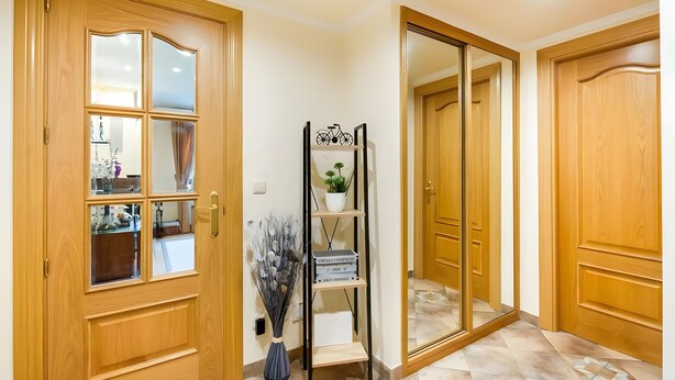 A wooden door with a glass panel, a mirror, and a small shelf with decorative items. - Casa Rural Juanikoenea – Traditional House with Garden and Jacuzzi in Leitza (Leitza)