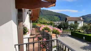 A balcony with a view of a green hillside and a white building with a red roof. - Casa Rural Juanikoenea – Traditional House with Garden and Jacuzzi in Leitza (Leitza)