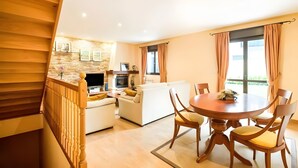 A modern living room with a dining area, wooden staircase, and a kitchen in the background. - Casa Rural Juanikoenea – Traditional House with Garden and Jacuzzi in Leitza (Leitza)