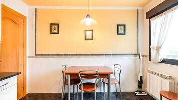 Un comedor con una mesa, sillas, una lámpara en el techo y cuadros en la pared.