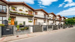 A row of modern multi-story residential buildings with balconies, a gated entrance, and a clear sky. - Casa Rural Juanikoenea – Traditional House with Garden and Jacuzzi in Leitza (Leitza)