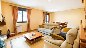 A living room with a sofa, coffee table, and dining area. - Casa Rural Juanikoenea – Traditional House with Garden and Jacuzzi in Leitza (Leitza)