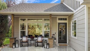Una casa con un patio techado, mobiliario exterior y una chimenea.