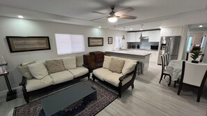 Ein modernes Wohnzimmer mit einer Sofagarnitur, einem Couchtisch und einem Essbereich mit Stühlen und einem Tisch.