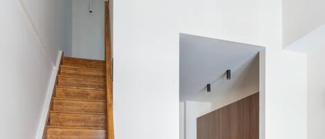 Un escalier en bois mène à une cuisine dotée de meubles en bois et d’appareils électroménagers modernes.
