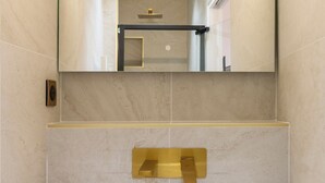 A modern bathroom with a large mirror, a gold towel rack, and a white sink. - Spacious Paris Duplex for 4 Near Bastille (Paris)
