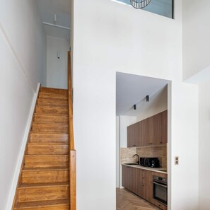 A wooden staircase leading to a kitchen with wooden cabinets and a microwave. - Spacious Paris Duplex for 4 Near Bastille (Paris)
