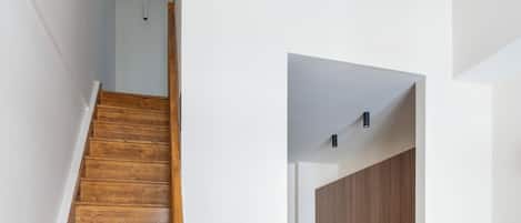 A wooden staircase leading to a kitchen with wooden cabinets and modern appliances.