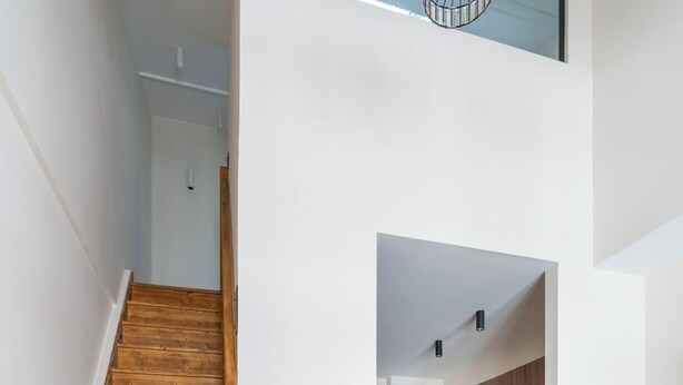 A wooden staircase leading to a kitchen with wooden cabinets and modern appliances. - Spacious Paris Duplex for 4 Near Bastille (Paris)