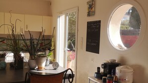A kitchen with a bar stool, potted plants, a chalkboard menu, a coffee machine, and a window with a view of greenery. - House 50 m from portissol beach. All amenities within walking distance. (Sanary-sur-Mer)