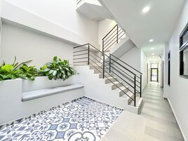 Un interior moderno con una escalera, paredes blancas y suelo estampado.