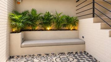 A corner seating area with a bench, potted plants, and a patterned floor.