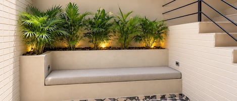 A corner seating area with a bench, potted plants, and a patterned floor.