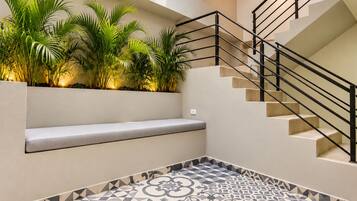 A modern interior with a staircase, a bench, and patterned flooring.