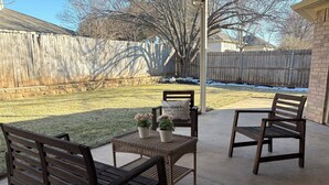 Un patio con dos bancos de madera, una mesita y plantas en macetas.
