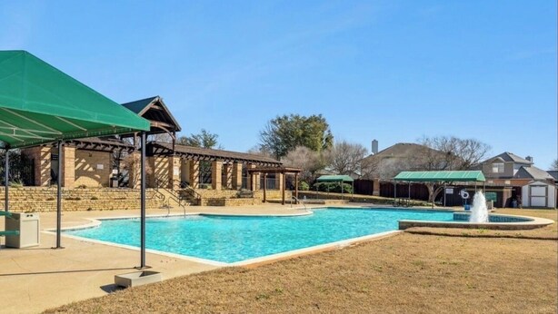 Zona de piscina con un pabellón cubierto, un edificio de piedra y un patio cercado.
