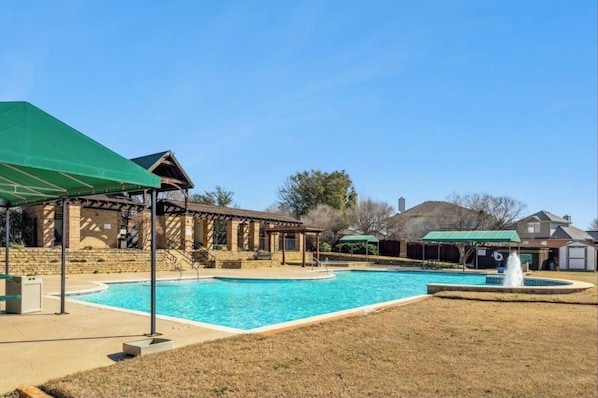 Zona de piscina con un pabellón cubierto, un edificio de piedra y un patio cercado.