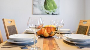 A dining table set with plates, glasses, and a fruit bowl.