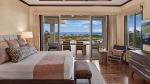 A hotel room with a bed, a dining table with chairs, a TV, and a view of the ocean. - Wai'ula'ula Villa 409 Four Bedroom (Kohala Coast)