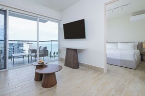 Ein modernes Hotelzimmer mit großem Balkon, Flachbildfernseher, einem Bett und einem kleinen runden Tisch.
