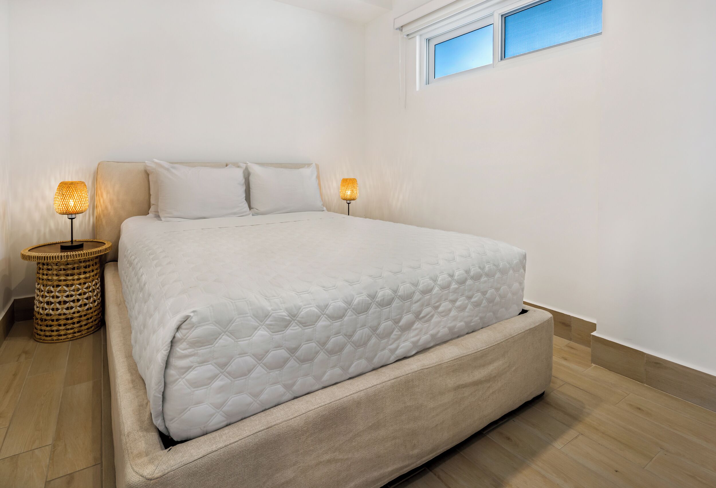 Un dormitorio minimalista con una cama grande, dos lámparas de noche y un ventanal.