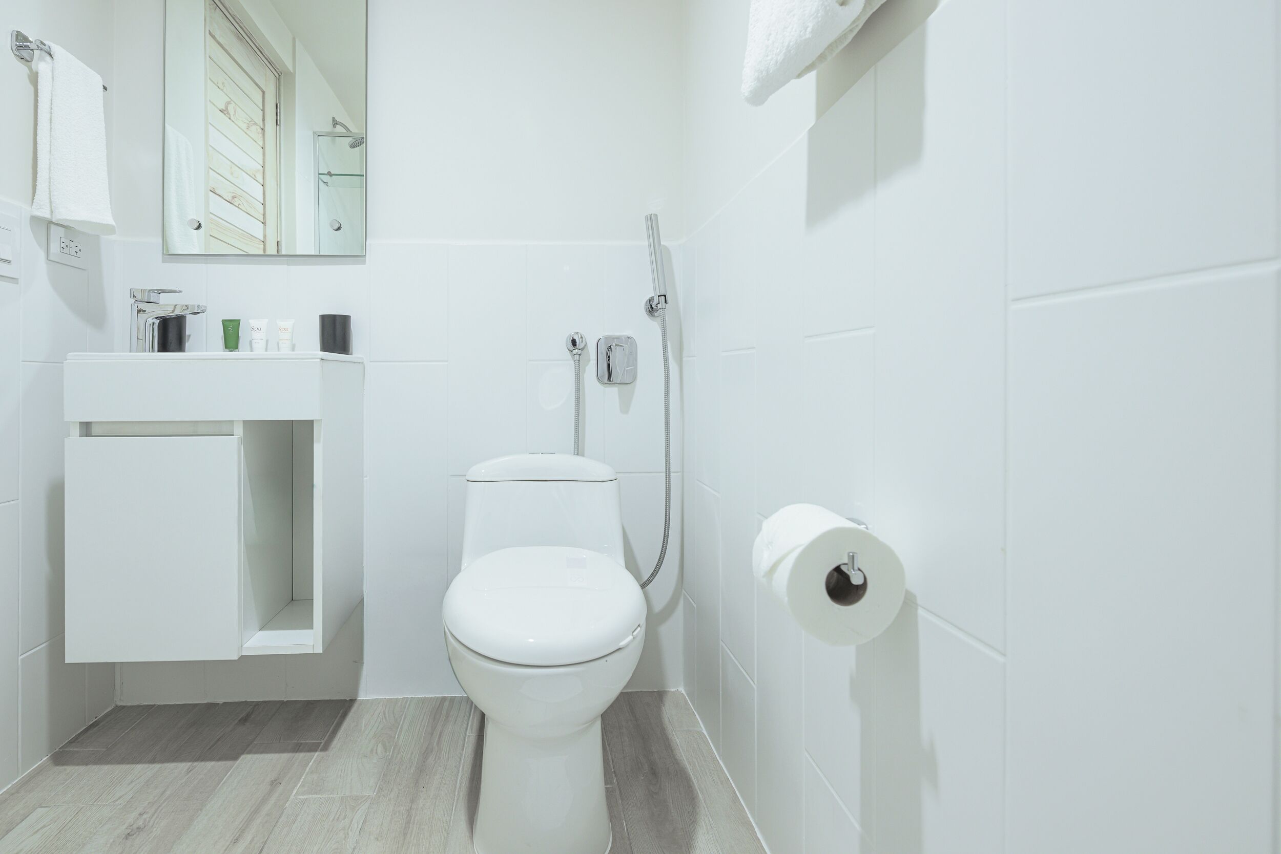 Un baño moderno con inodoro, lavamanos, espejo y ducha.
