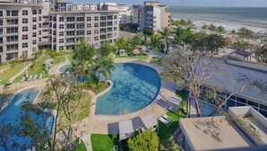 Un hotel moderno con una piscina grande, varios balcones y vistas al océano.