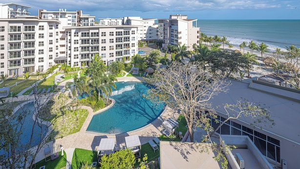 Un resort con piscina, vista a la playa y varias edificaciones.