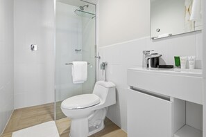 Ein modernes Badezimmer mit Duschkabine aus Glas, einer weißen Toilette und einem Waschtisch mit Pflegeprodukten.