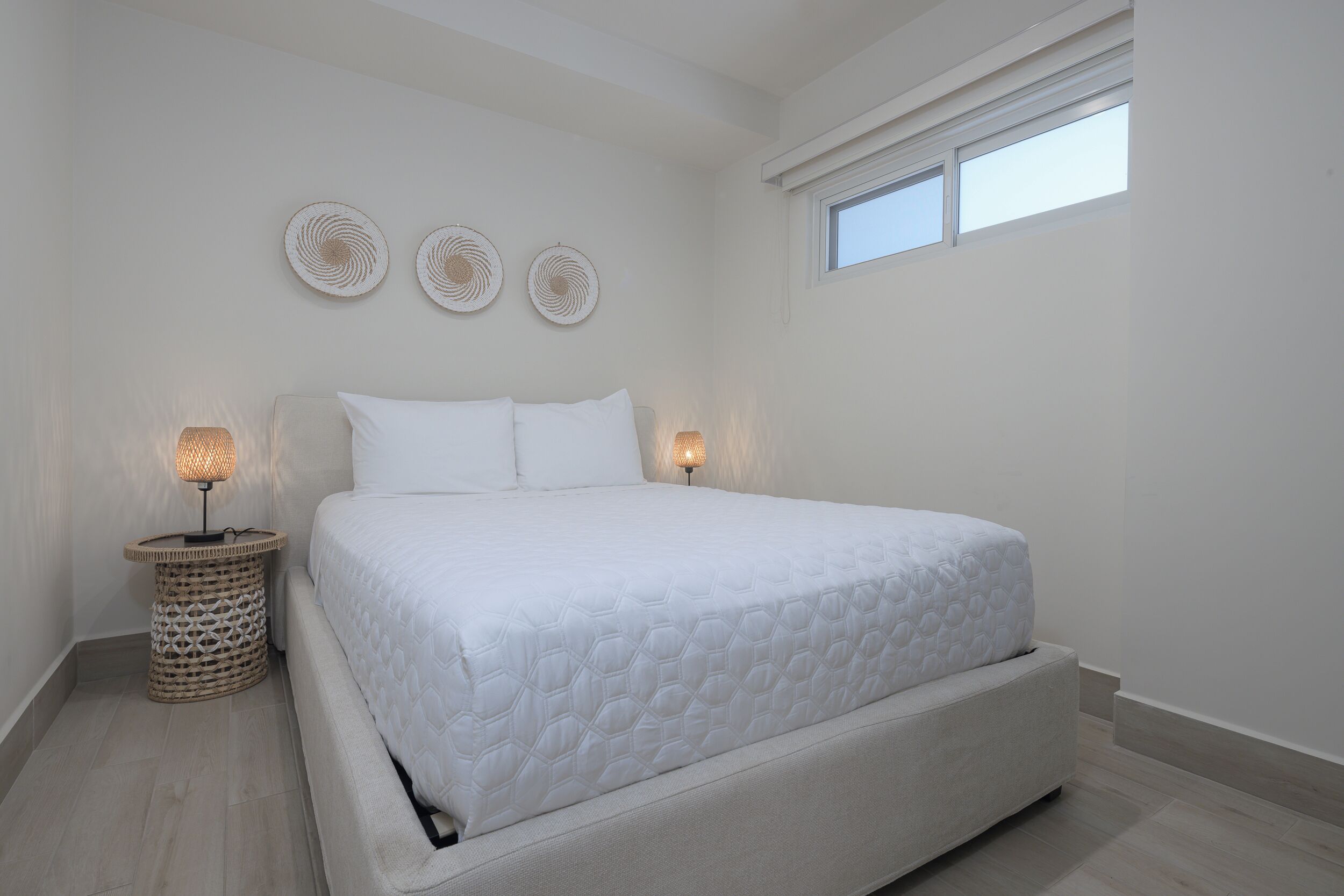 A bedroom with a large bed, two bedside lamps, and three wall-mounted circular decorations.