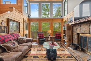 A cozy cabin interior with a fireplace, wooden walls, a glass coffee table, and a leather sofa. - ONE Beary Good View 3BR-2BA in Gatlinburg Sleeps 9 (Gatlinburg)