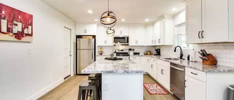 A modern kitchen with white cabinetry, a central island, and a hanging light fixture.