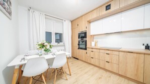 Una cocina moderna con armarios blancos, una encimera de madera y un comedor con mesa y sillas blancas.