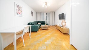 Un salón moderno con un sofá verde, una mesa blanca y un suelo de madera con diseño de espiga.