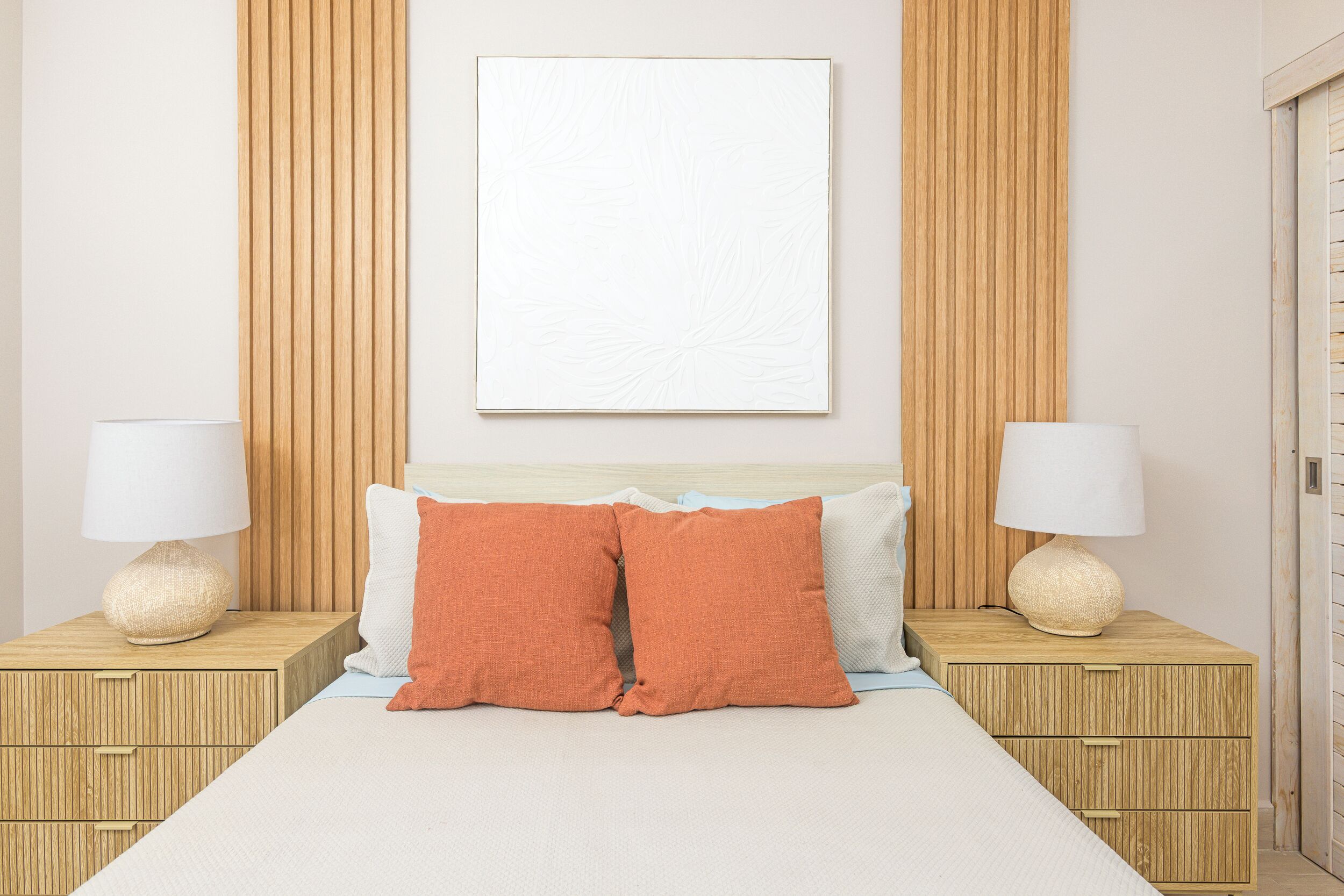 A neatly arranged bedroom with a bed, two nightstands, and a wall-mounted lamp.