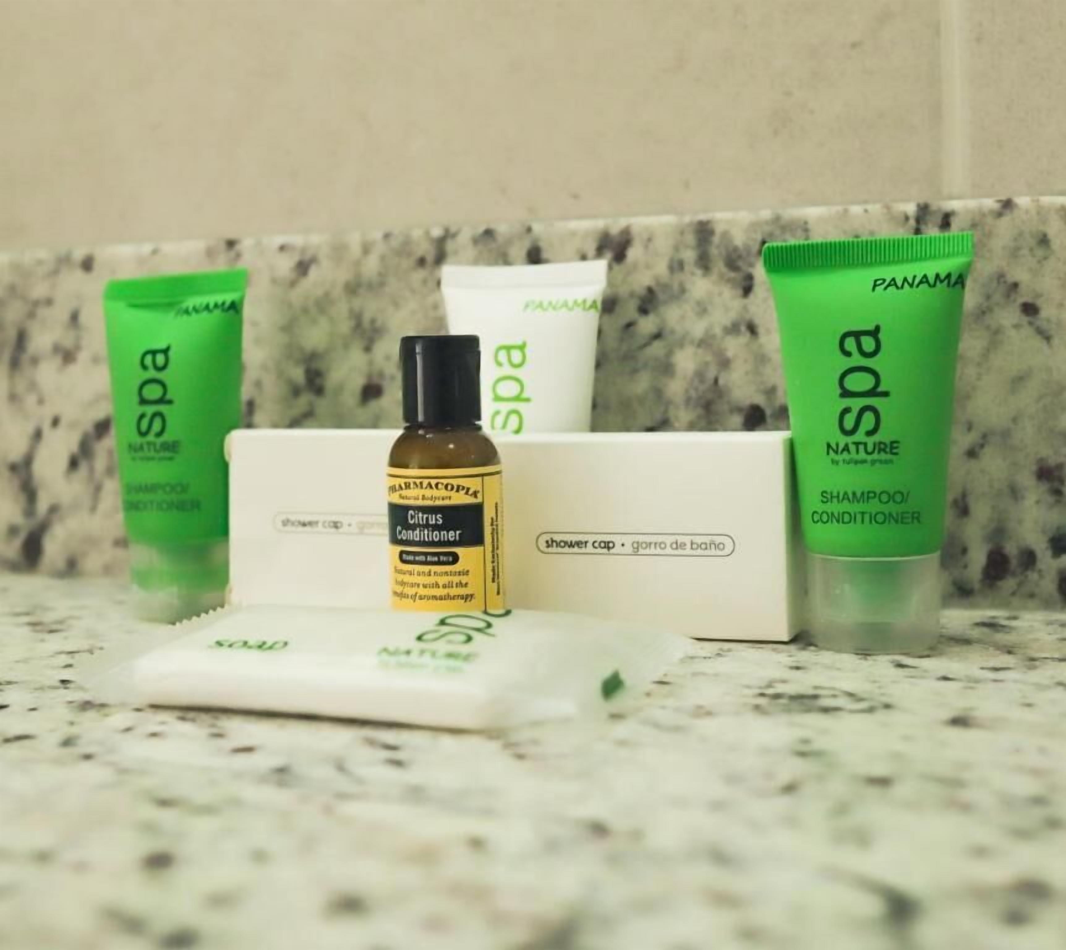 Una encimera de baño con diversos productos de spa, incluyendo un gorro de ducha, una botella de acondicionador cítrico y dos tubos de champú o acondicionador.