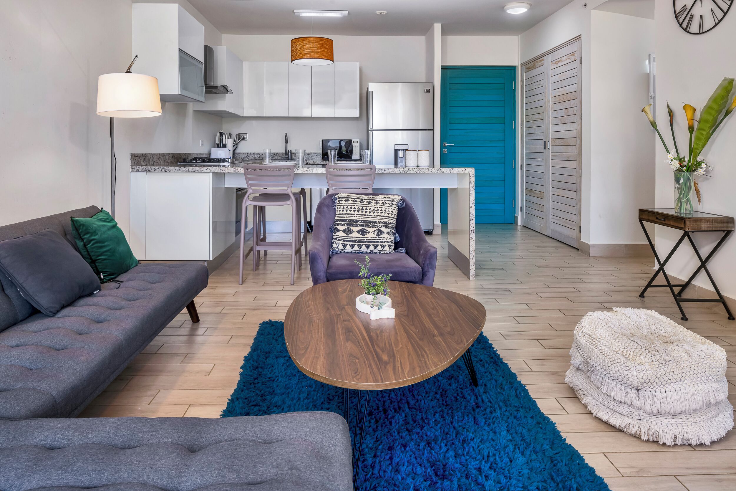 Un salon moderne avec un canapé gris, une table basse ronde et un tapis bleu.