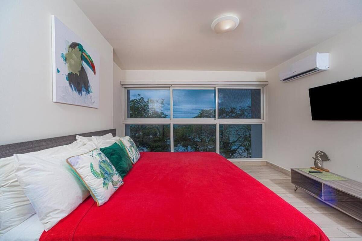 Een slaapkamer met een groot bed, een raam met uitzicht, een wandtelevisie en een airconditioning.