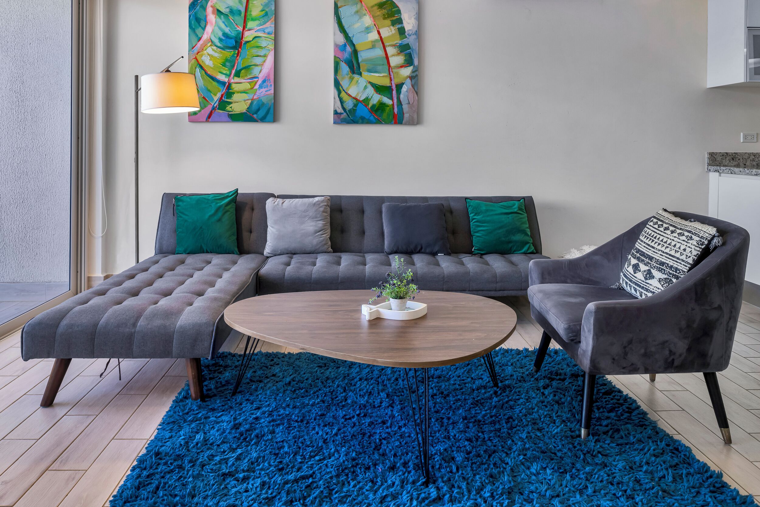 Una sala de estar moderna con un sofá modular, una mesa de centro redonda y un tapete de pelo azul.