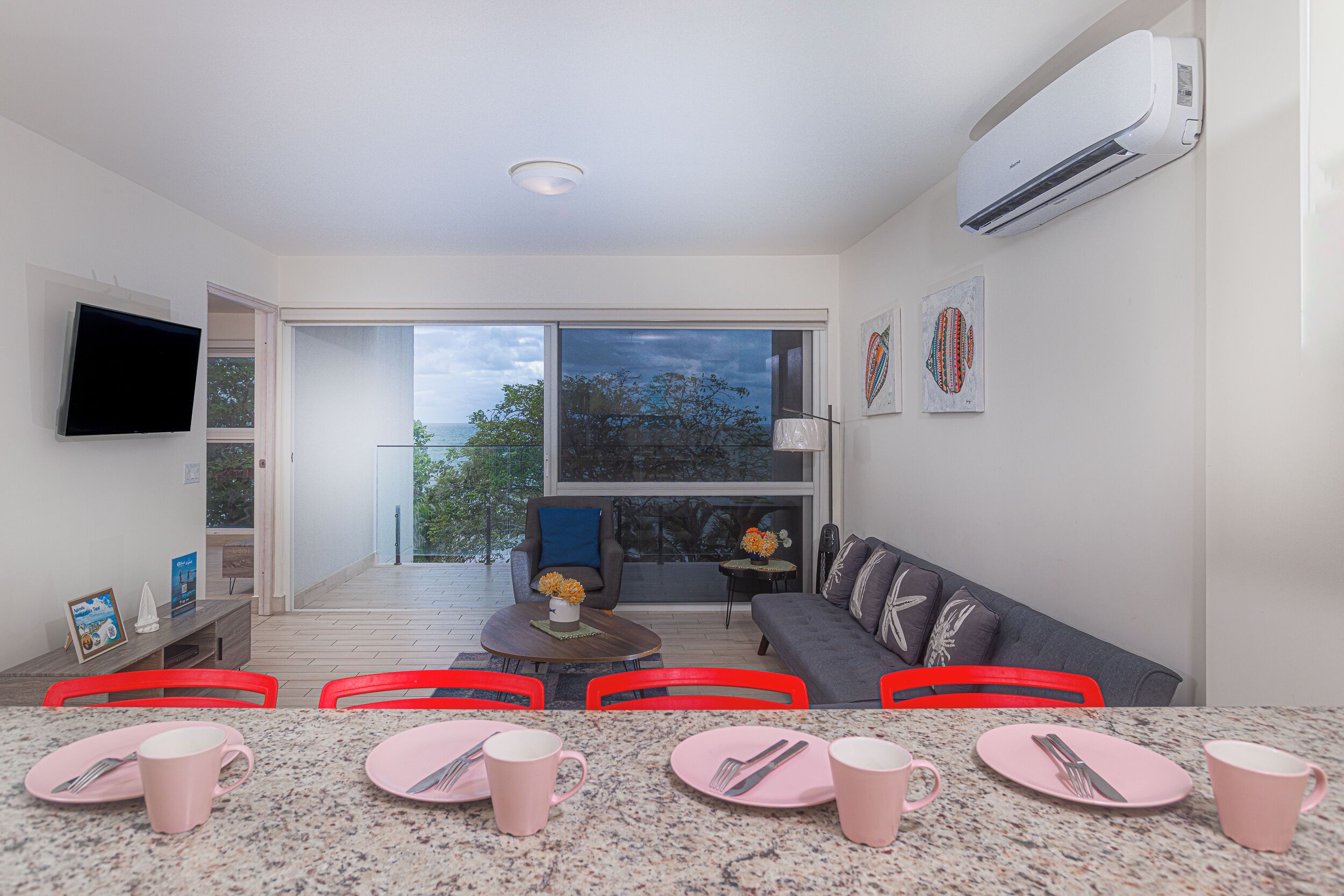 A modern living room with a dining area, large windows, and a flat-screen TV.