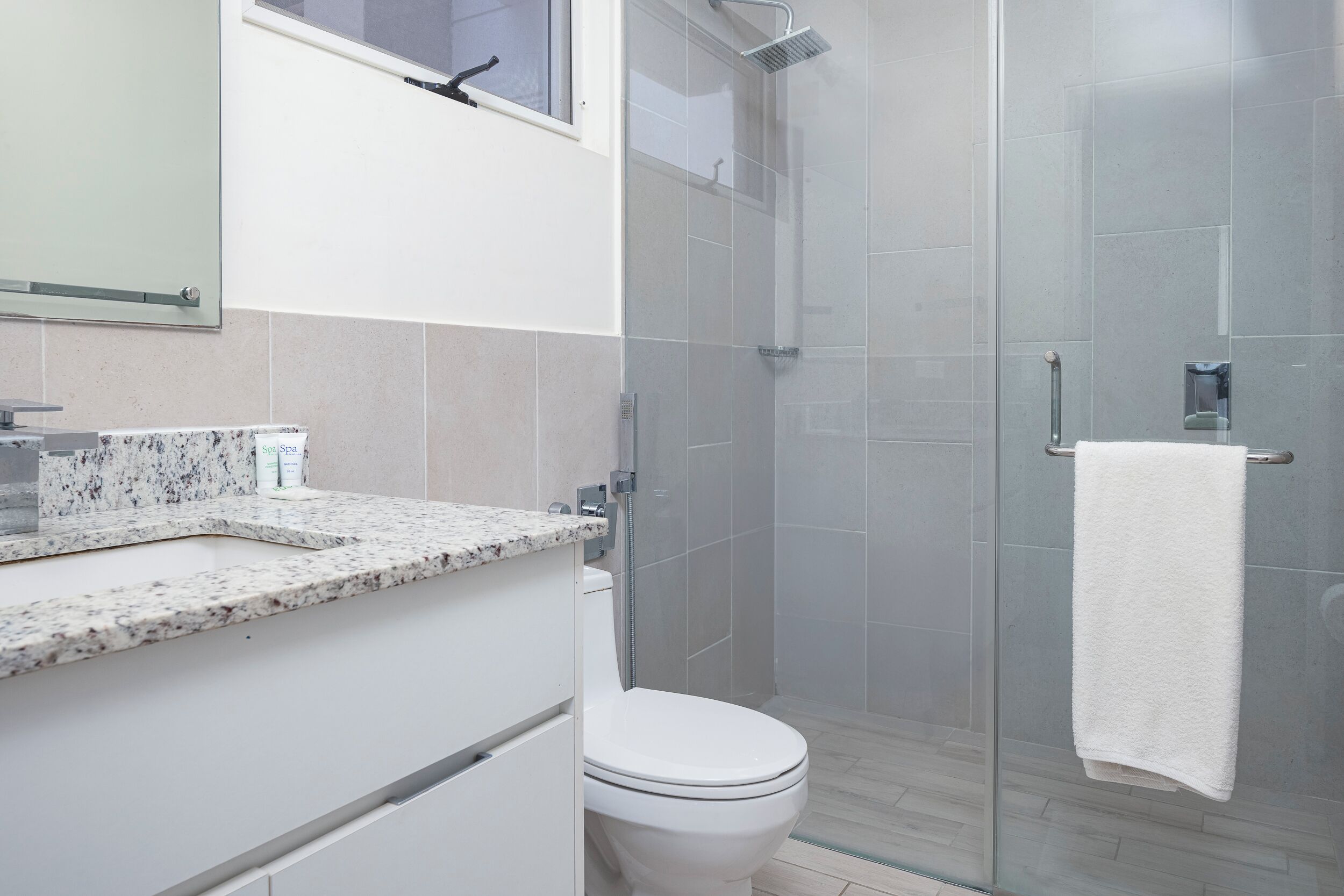 Ein modernes Badezimmer mit Duschkabine aus Glas, einer weißen Toilette und einer Marmorarbeitsplatte.