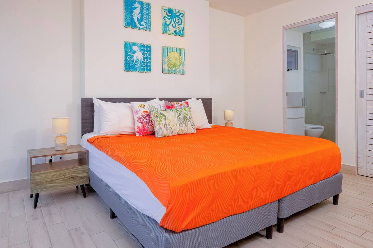 Een slaapkamer met een groot bed, twee nachtkastjes en een douchehoek.